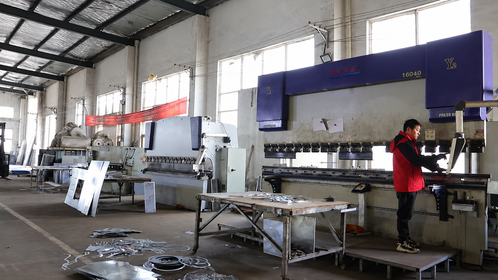 Metal bending machine shaping workpieces for outdoor furniture and public facility production.